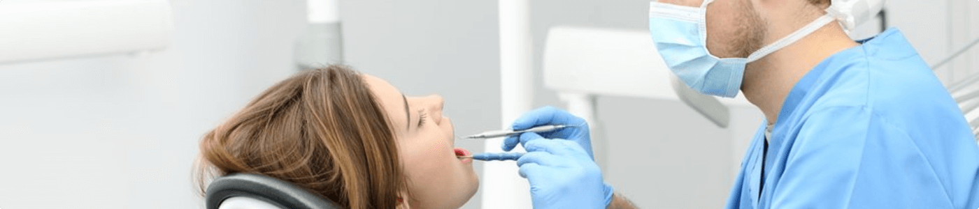 A woman is getting her teeth cleaned by a dentist.