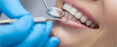 A woman's teeth being examined by a dental hygienist.