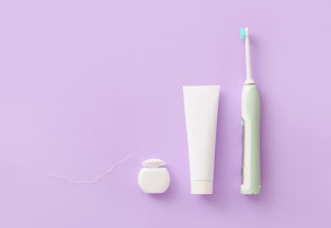 A toothbrush and toothpaste on a purple background.