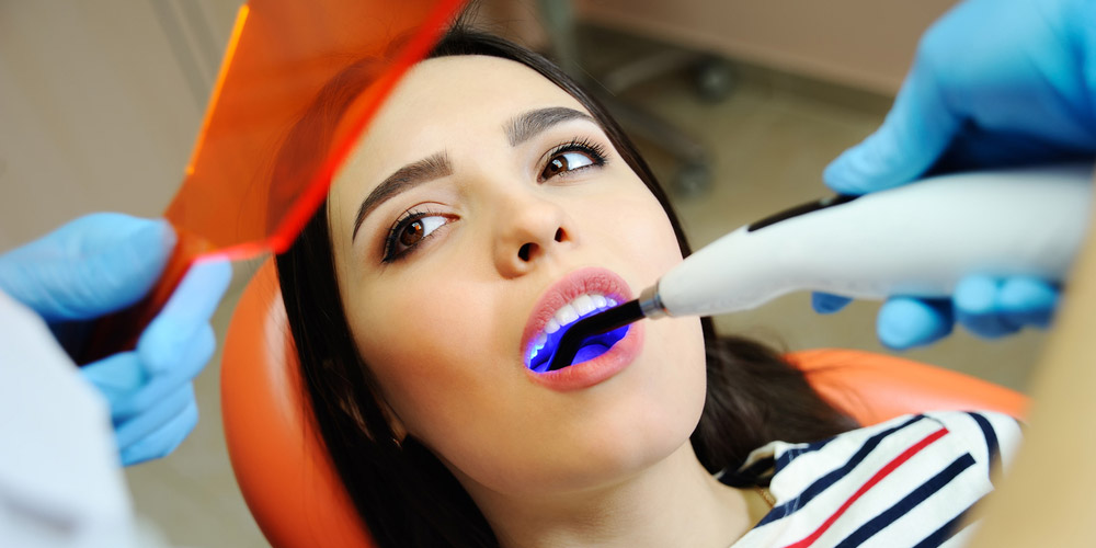 A woman is getting her teeth cleaned by a dentist.