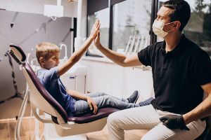 A dentist giving a high five to a child in a dental chair.