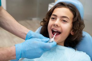 A child is being examined by a dentist in a dental chair.