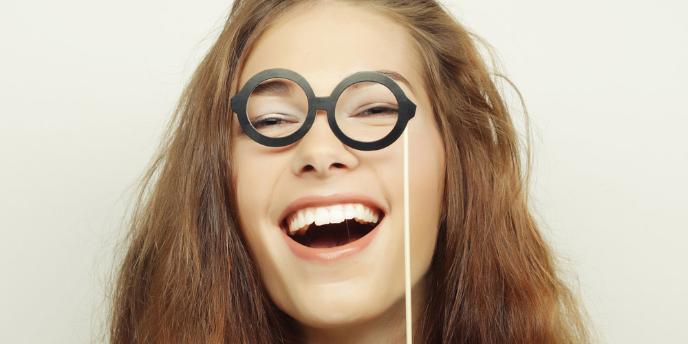 A woman wearing glasses with a smile on her face.