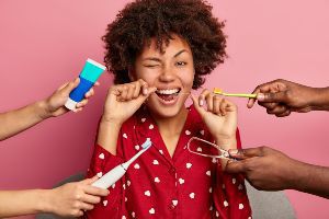 A group of people brushing their teeth in front of a pink background.