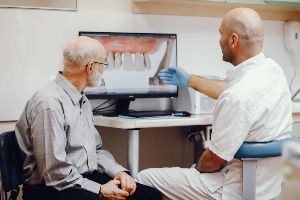 A dentist is looking at a patient's teeth on a computer screen.