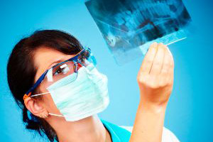 A female dentist looking at an x - ray.