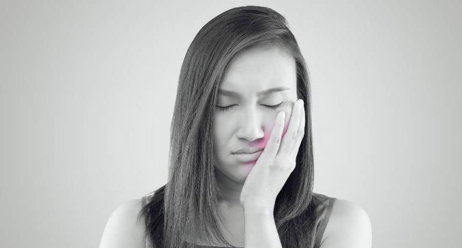 A woman is holding her hand to her face.