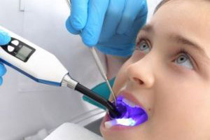 A little girl is getting her teeth cleaned by a dentist.