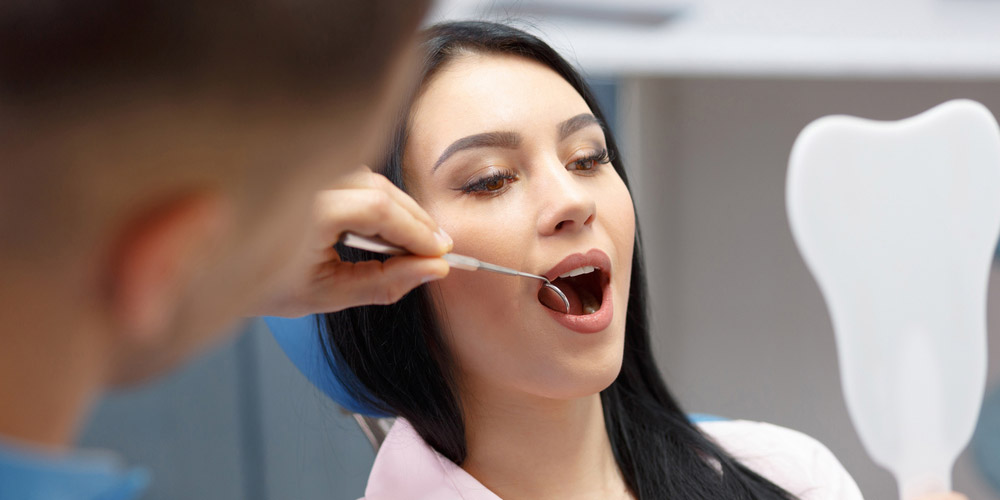 A woman is being examined by a dentist.