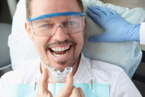 A man is holding a dental device in his mouth.