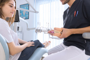 A dentist is talking to a patient in a dental chair.