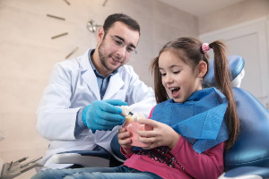 A young girl sitting in a dentist's chair.