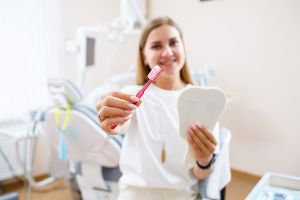 A woman is holding a toothbrush in front of a dental chair.