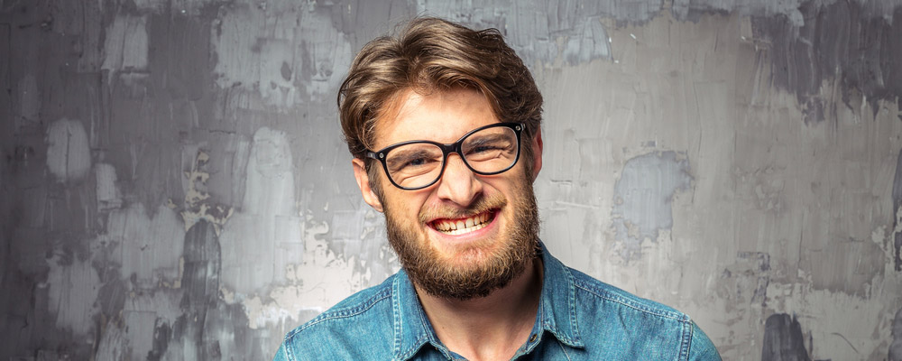 A man with glasses and a beard is smiling.