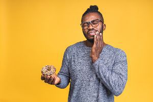 A man holding a doughnut on a yellow background.