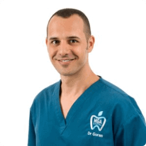 A man in blue scrubs posing for a photo.