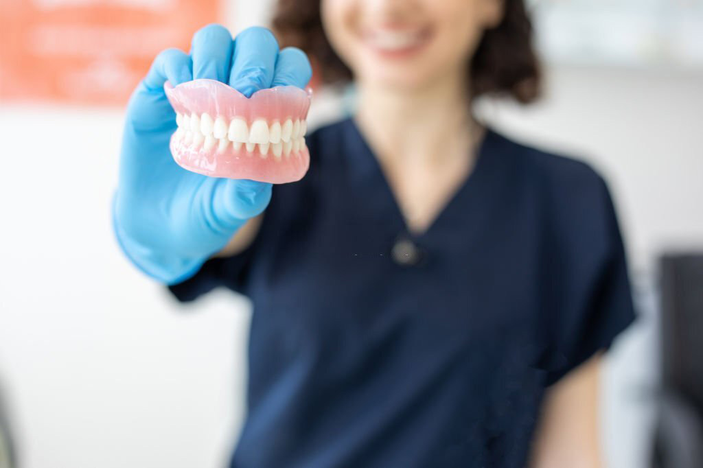 A dentist demonstrating dental implants with a model of a tooth.